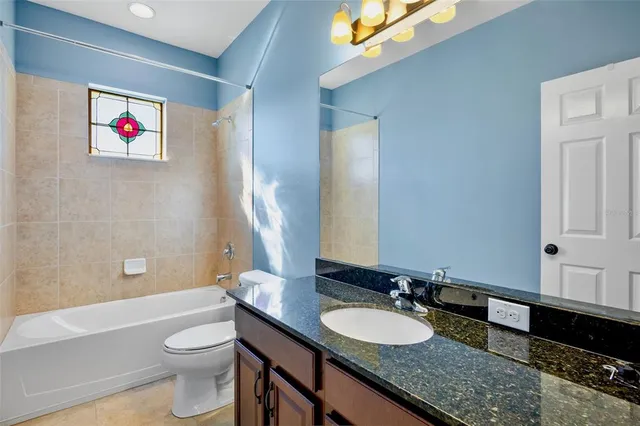 a bathroom with a granite countertop bathtub sink vanity mirror and toilet