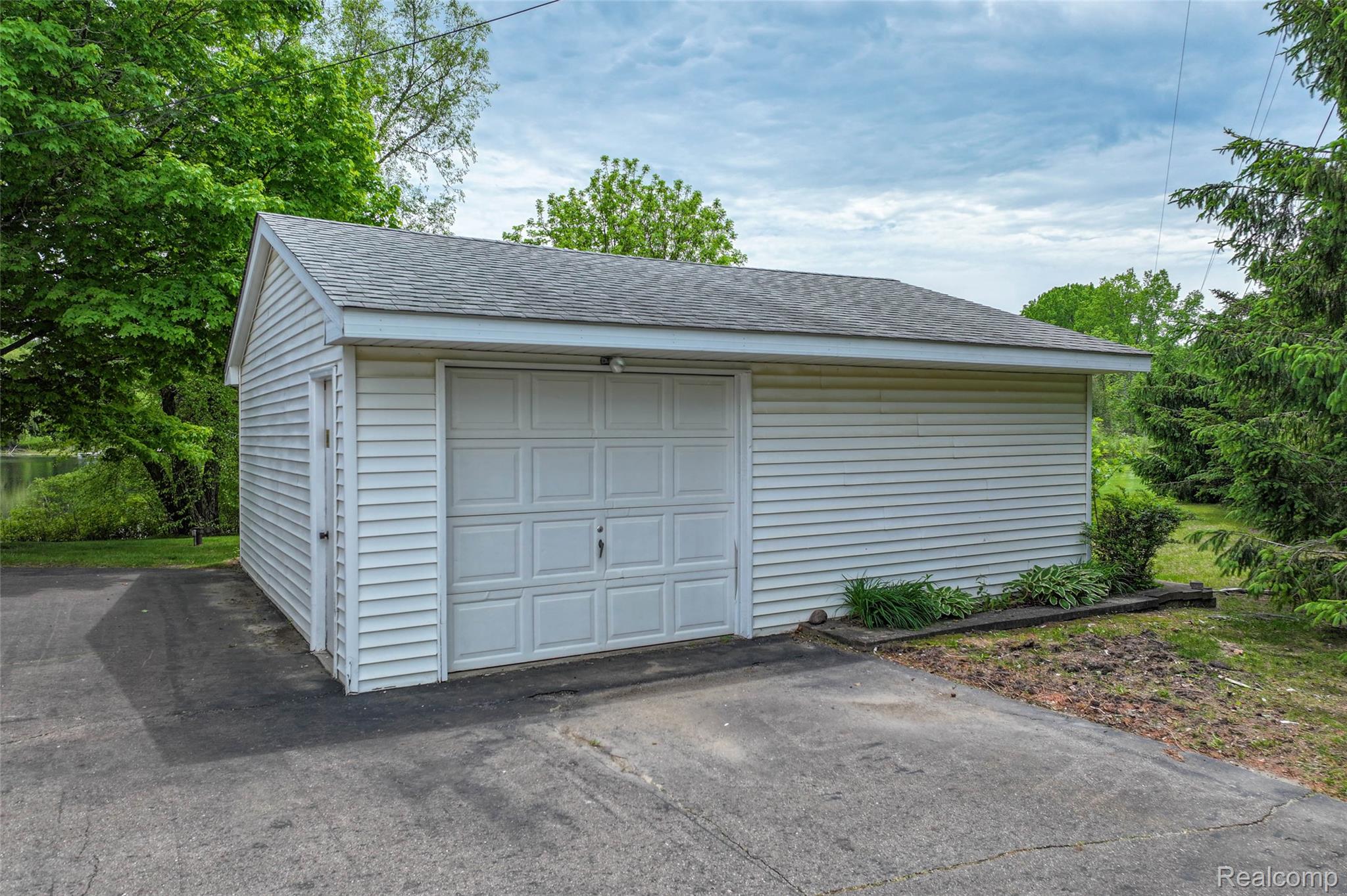 422 East Road Holly, MI 48442 - Photo 12 of 51 Detached garage with white panel siding, a single overhead door, and a separate pedestrian entry door