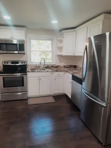 a kitchen with granite countertop a refrigerator stove and sink