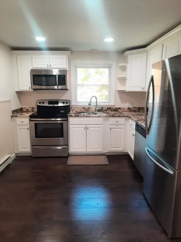 a kitchen with granite countertop a refrigerator stove and wooden floor