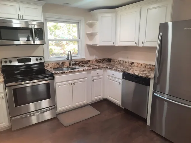 a kitchen with granite countertop white cabinets and stainless steel appliances
