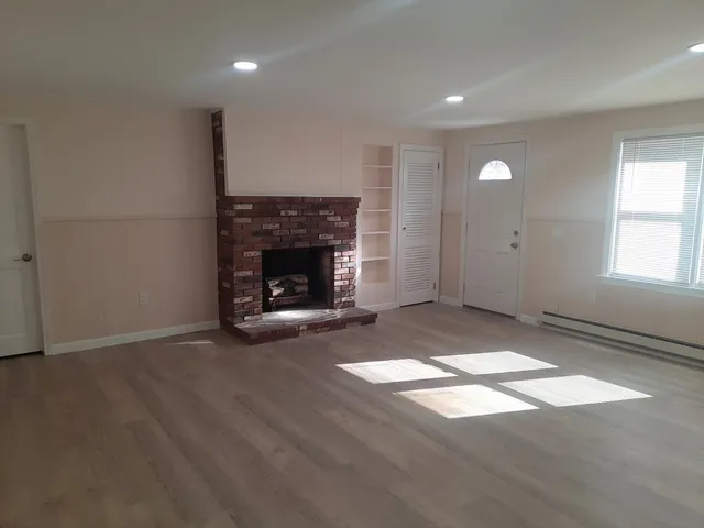a view of an empty room with window and fire place