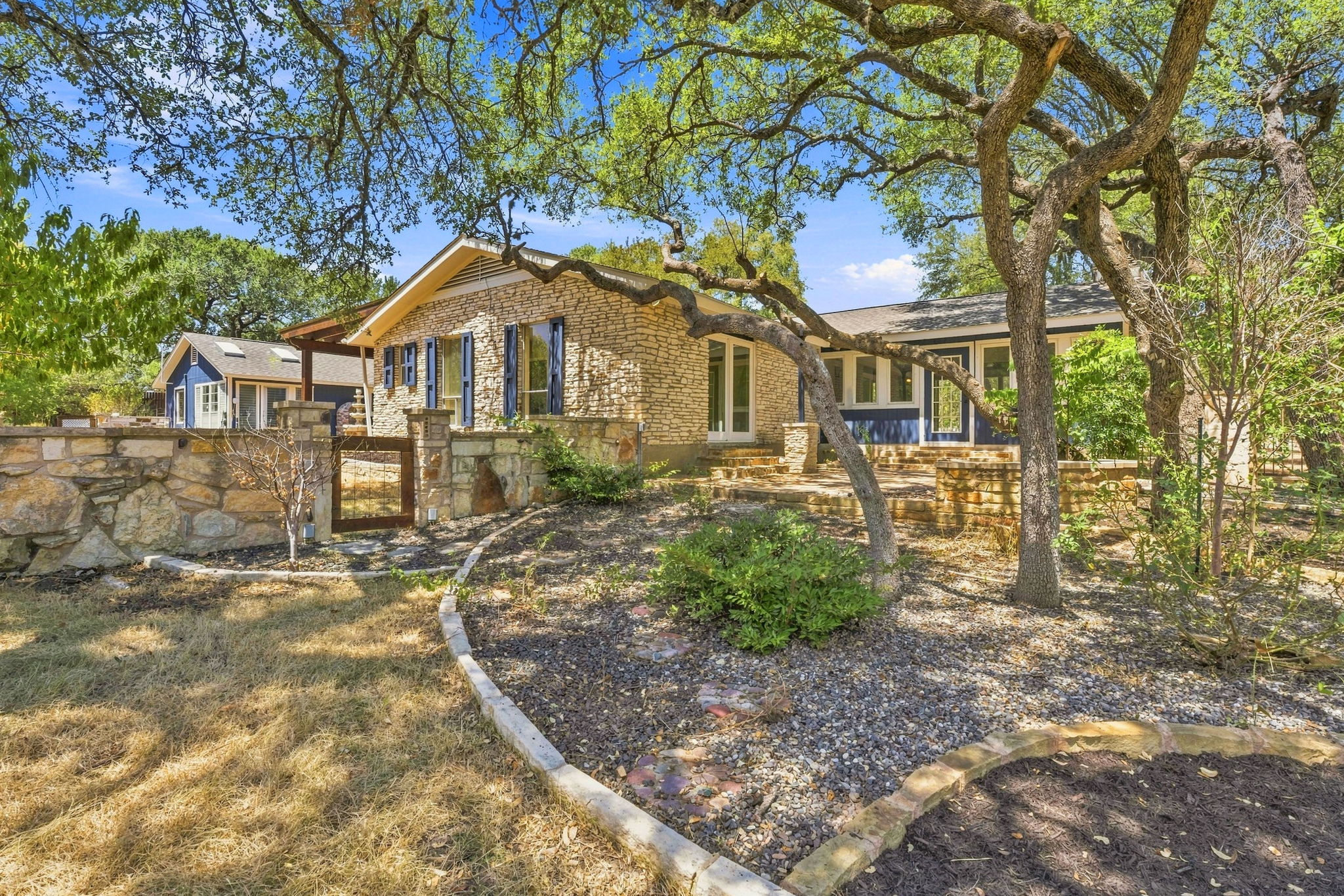 3809 Wyldwood Road Austin, TX 78739 - Photo 23 of 40 Mature shade trees frame a classic stone exterior with gated entry and stone walls.