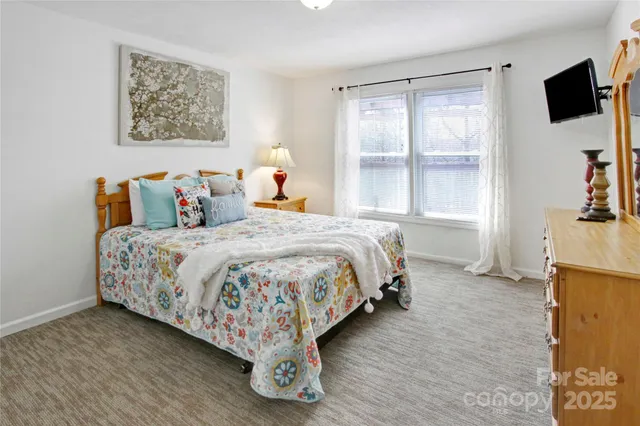 a bedroom with a bed and a flat tv screen on the dresser