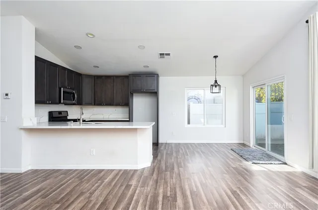 a kitchen with stainless steel appliances granite countertop a refrigerator a sink dishwasher a stove and white countertops with wooden floor