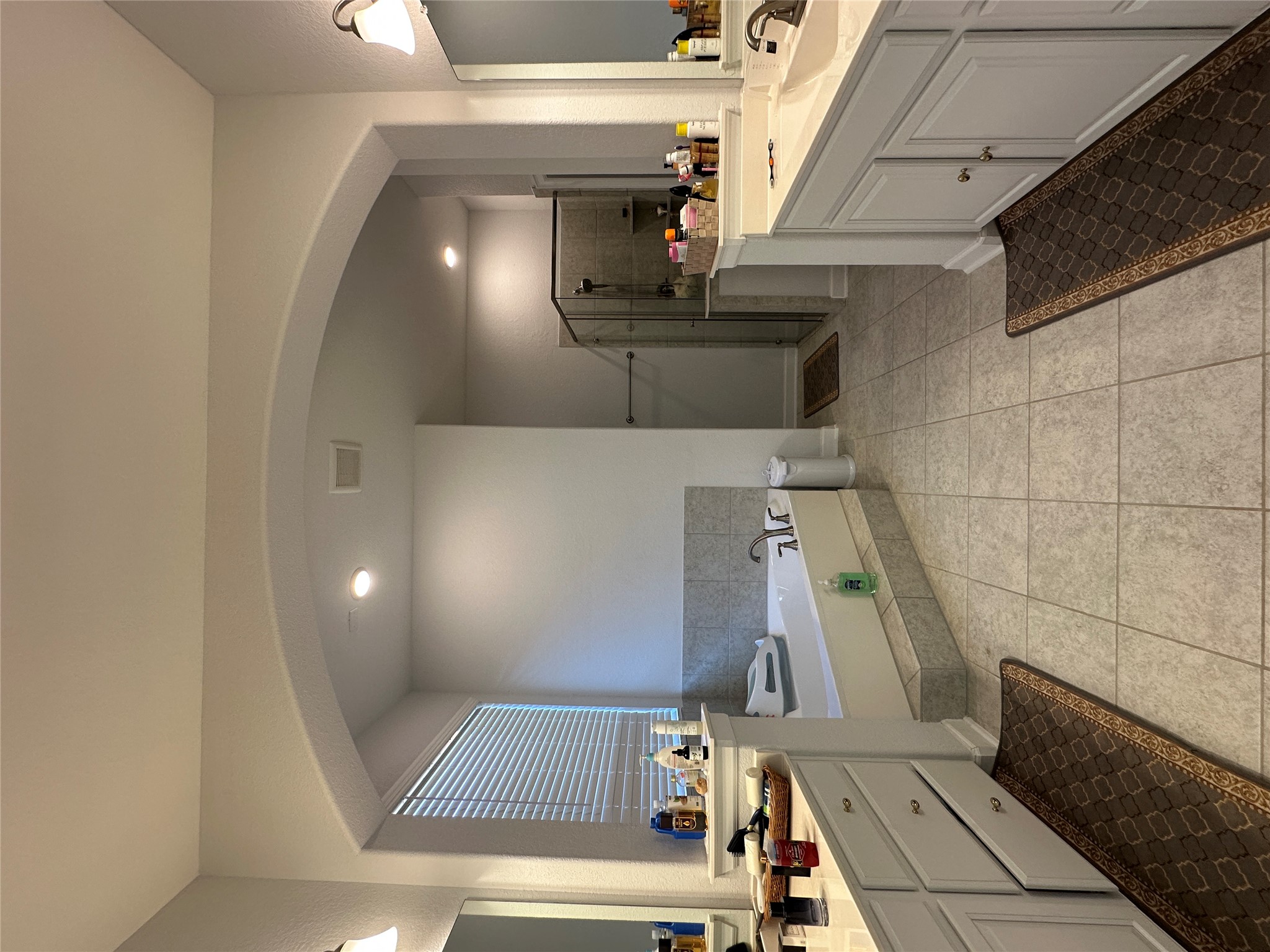 650 Wild Pecan Loop Buda, TX 78610 - Photo 11 of 28 Bathroom with two vanities, a bath, a stall shower, light tile patterned flooring, and recessed lighting
