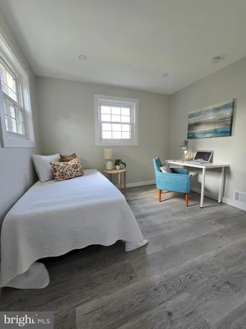 a bedroom with a bed a table and windows