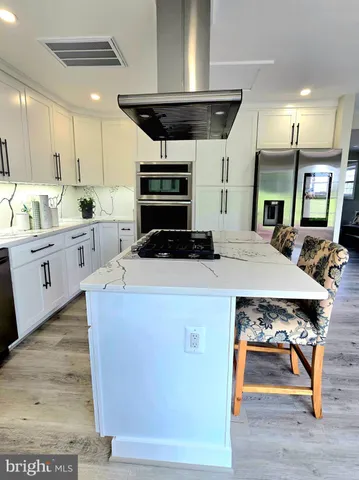 a kitchen with stainless steel appliances granite countertop a stove a sink dishwasher and a refrigerator with wooden floor