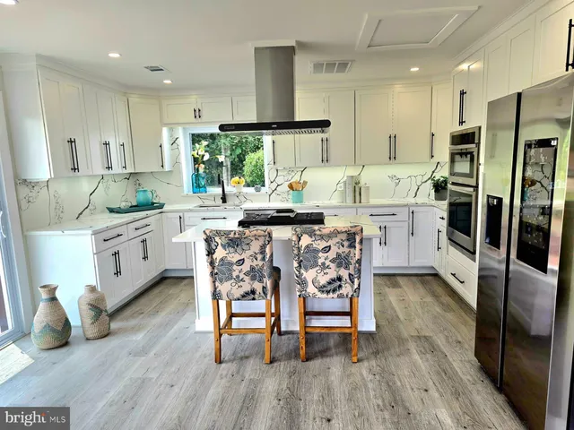 a kitchen with stainless steel appliances kitchen island granite countertop a table chairs sink and cabinets
