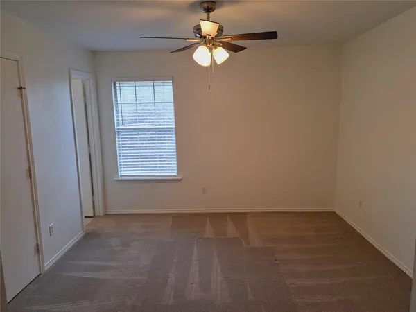 an empty room with windows and fan
