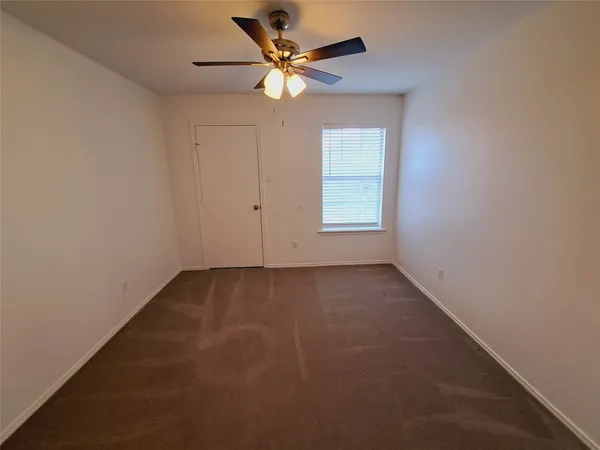 an empty room with a window and a ceiling fan