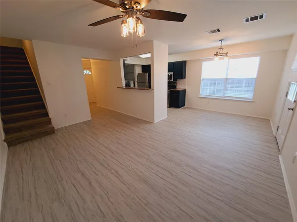 an empty room with wooden floor ceiling fan and windows