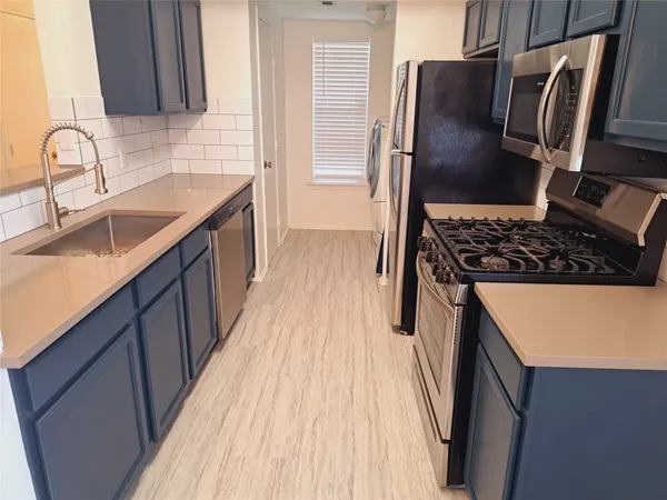 a kitchen with granite countertop a refrigerator stove and sink