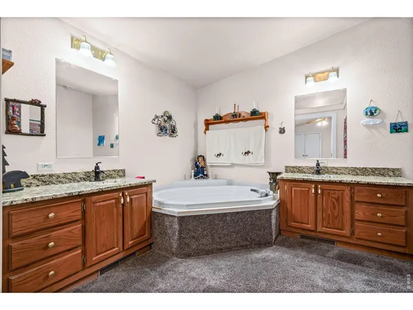 a spacious bathroom with a granite countertop double vanity sink a mirror and bathtub