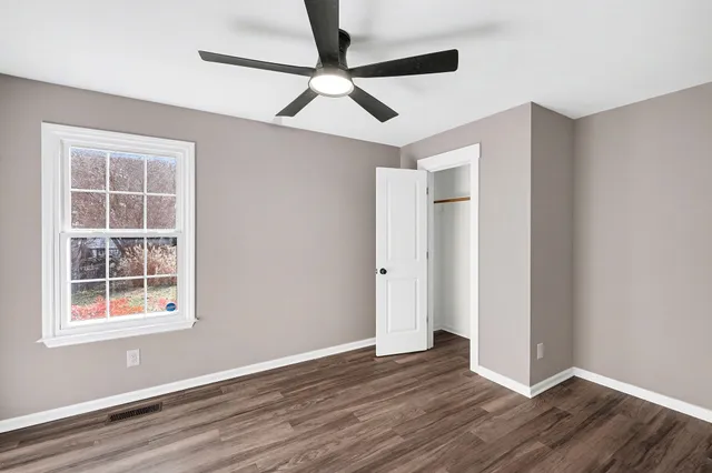 a view of empty room with wooden floor and fan