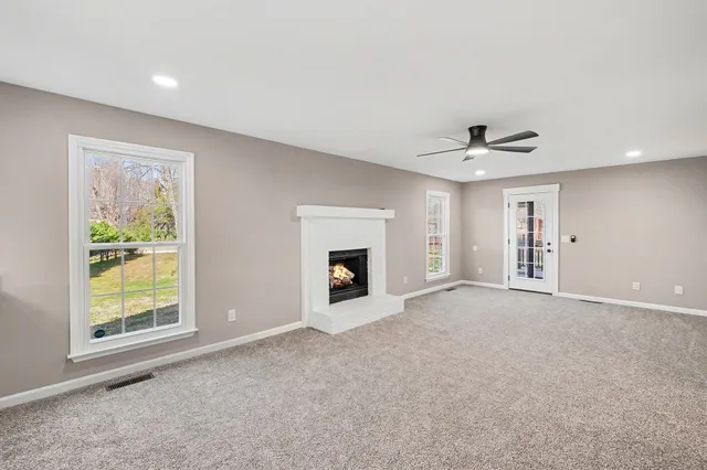an empty room with windows and fireplace