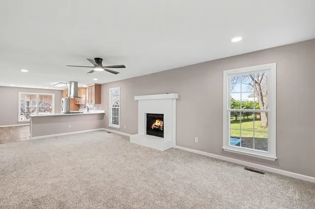 an empty room with windows and fireplace