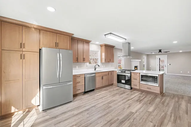 a kitchen with a refrigerator a stove top oven and wooden floors