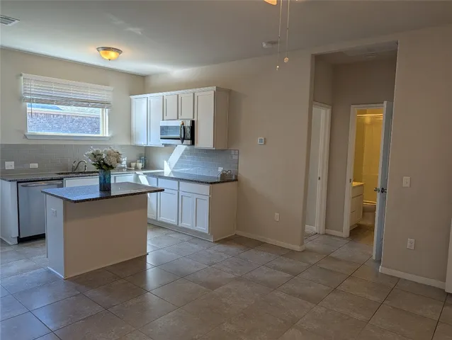 a large kitchen with granite countertop a sink and cabinets