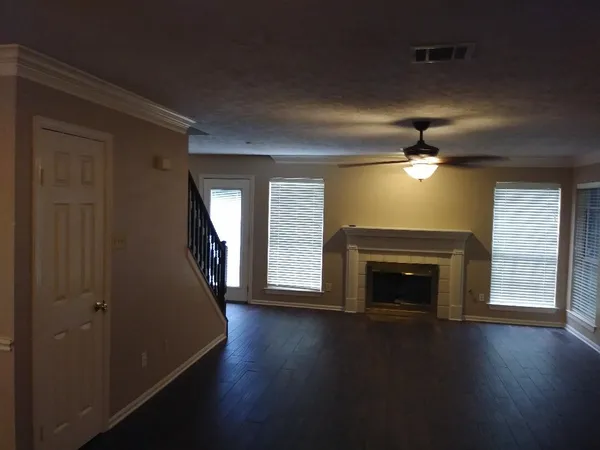 an empty room with wooden floor fireplace and windows