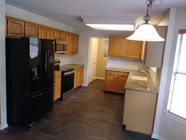 a kitchen with granite countertop a refrigerator a stove a sink a washer dryer and white cabinets
