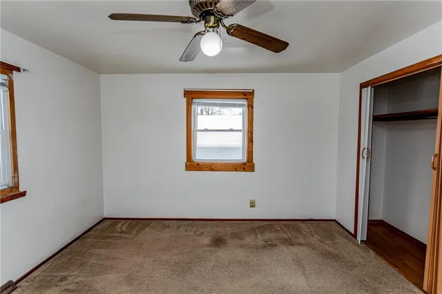 an empty room with a chandelier fan and closet