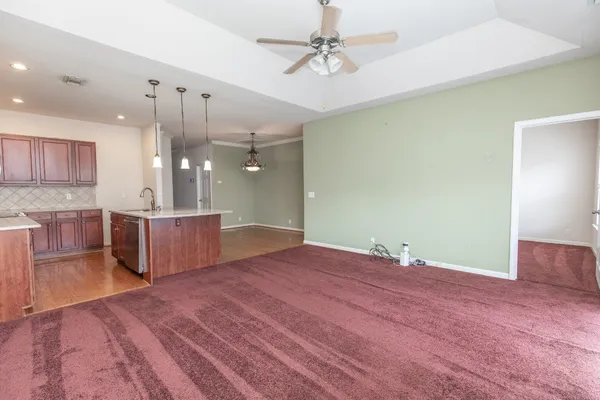 a view of an empty room with wooden floor and a ceiling fan