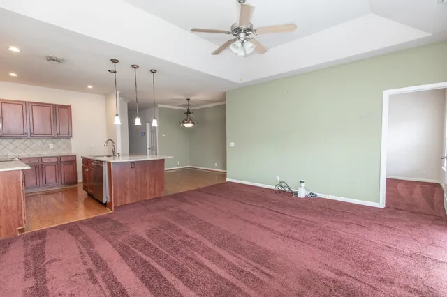 a view of an empty room with wooden floor and a ceiling fan