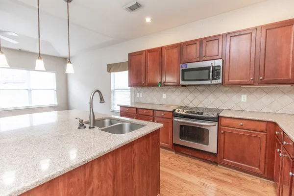 a kitchen with stainless steel appliances granite countertop a sink a stove a microwave and wooden cabinets