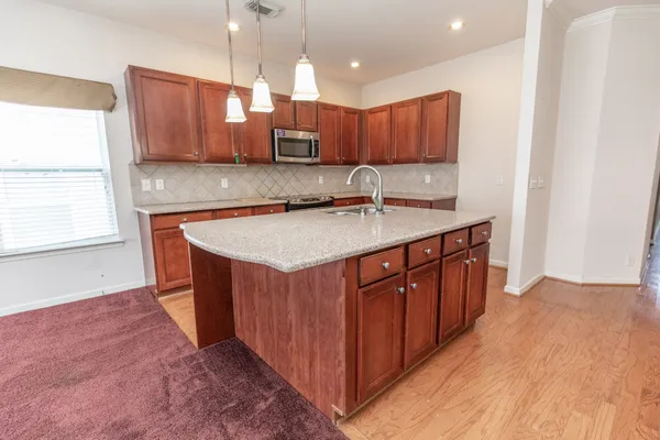 a kitchen with stainless steel appliances granite countertop wooden cabinets a sink and dishwasher a stove with wooden floor