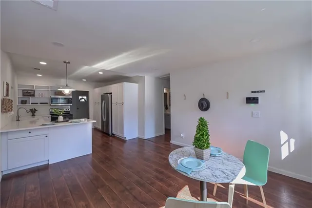 a living room with furniture dining table wooden floor and a kitchen view