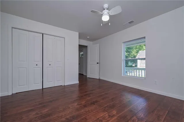 an empty room with wooden floor fan and windows