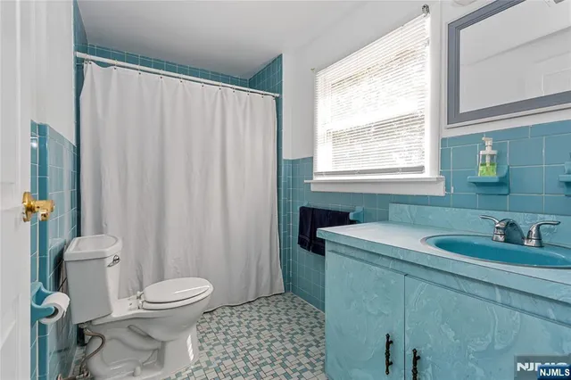 a bathroom with a sink a toilet a window and shower