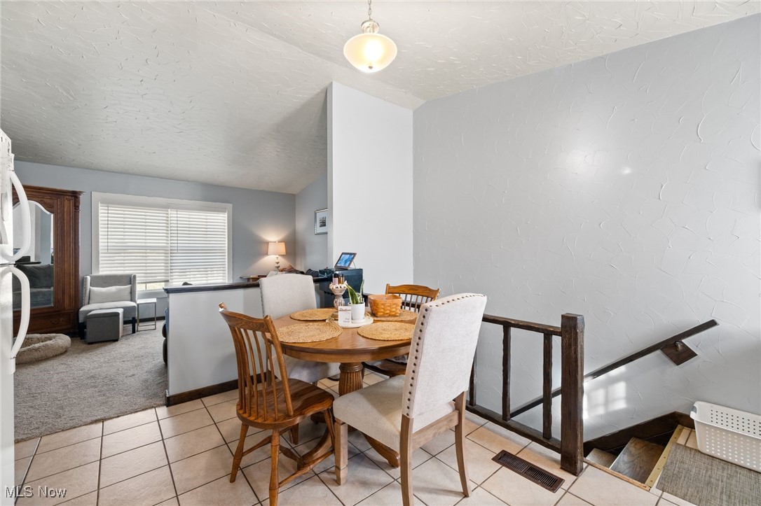 3213-3217 Pickle Road Green, OH 44312 - Photo 25 of 41 Dining space featuring light tile patterned flooring, a textured ceiling, light colored carpet, and vaulted ceiling