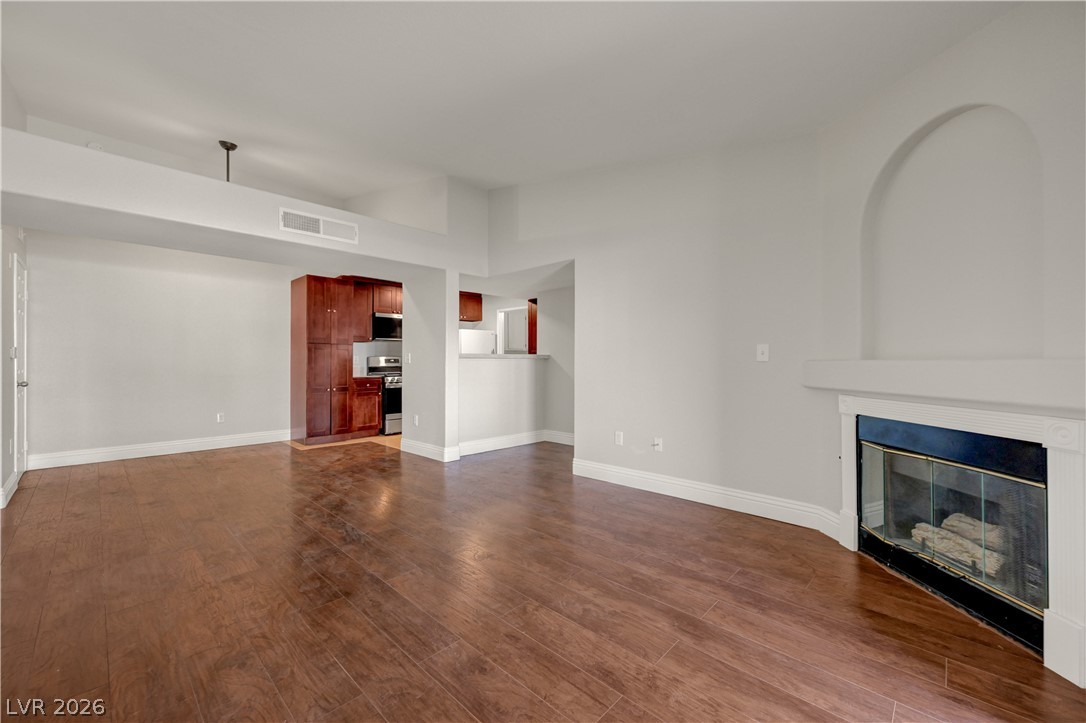 7885 West Flamingo Road, Unit 1050 Las Vegas, NV 89147 - Photo 5 of 62 Warm wood floors complement a cozy fireplace, crafting an inviting living space with an adjacent kitchen.