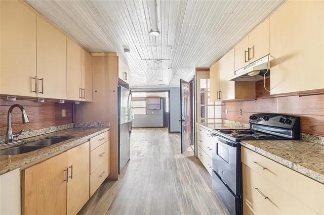 a kitchen with stainless steel appliances granite countertop a sink a stove and a refrigerator