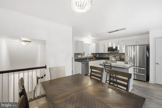 a kitchen with stainless steel appliances a stove a sink dishwasher a refrigerator white cabinets and wooden floor