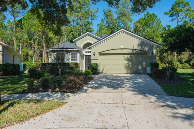 a view of a house with a yard plants and large tree
