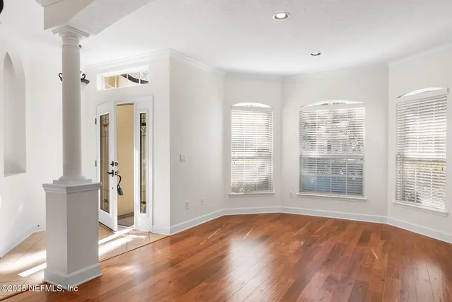 an empty room with wooden floor and windows