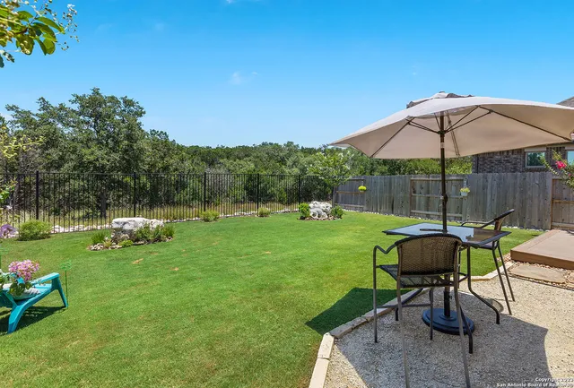 a view of a table and chairs under an umbrella in backyard