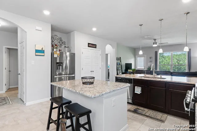 a kitchen with granite countertop kitchen island stainless steel appliances a sink and a refrigerator