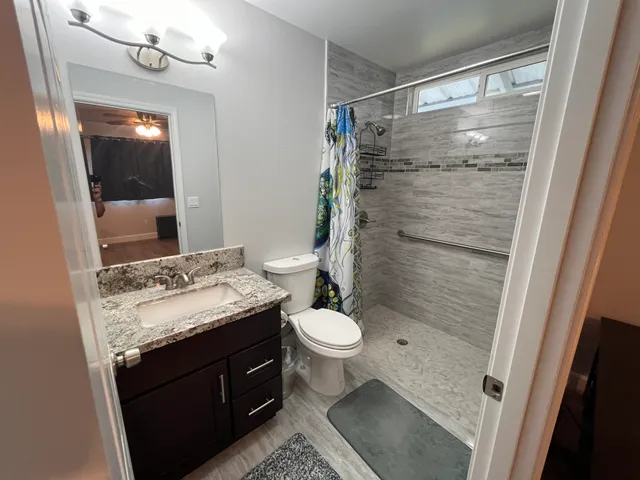 a bathroom with a granite countertop sink toilet and shower
