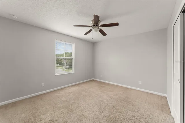 an empty room with a window and a fan