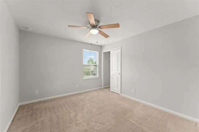 an empty room with windows and fan