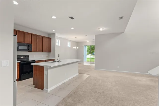 a large kitchen with stainless steel appliances a stove a refrigerator a sink a microwave and white cabinets