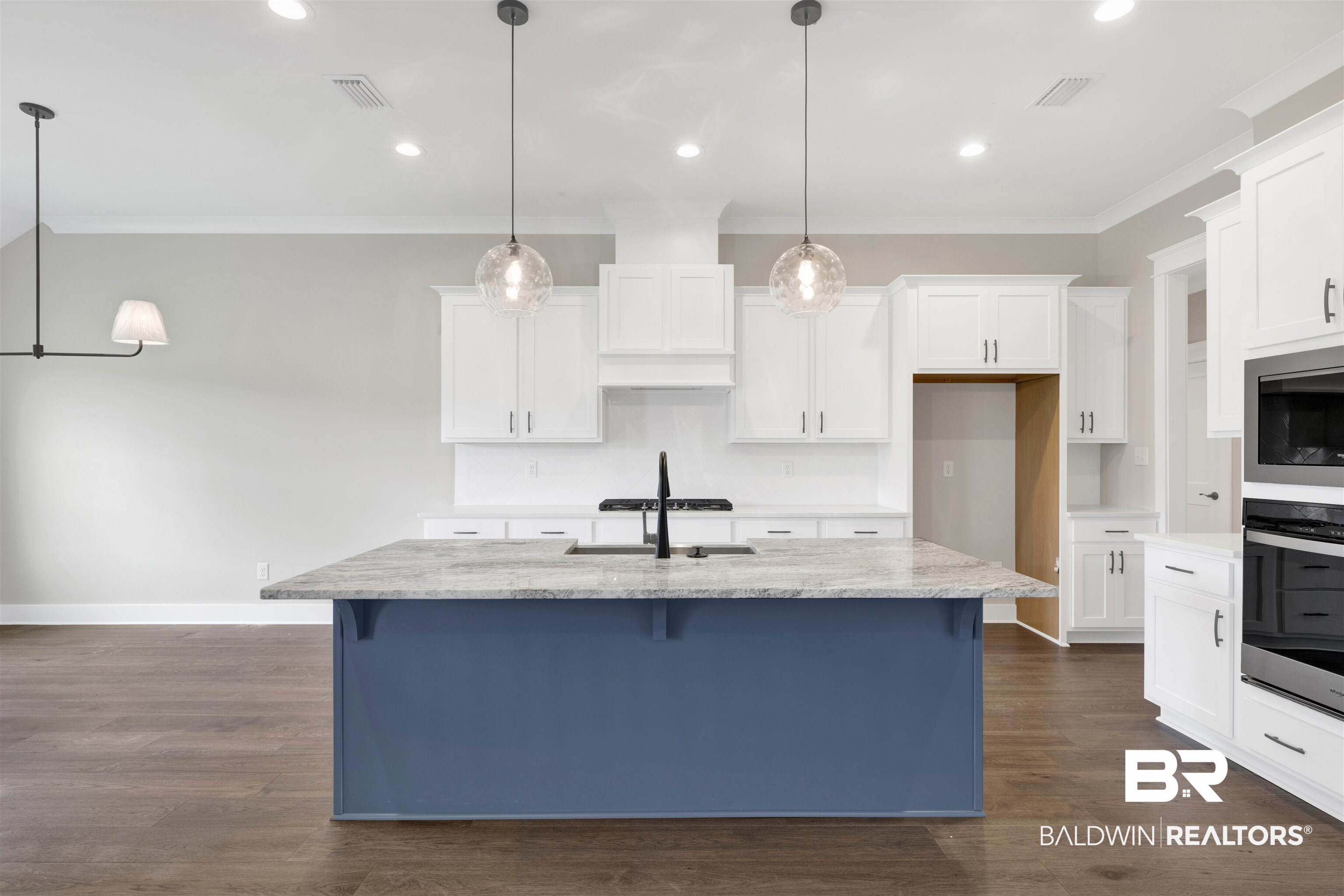 27315 Patch Pl Loop Daphne, AL 36526 - Photo 8 of 43 Kitchen with a kitchen bar, ornamental molding, a kitchen island with sink, light stone countertops, and wood floors