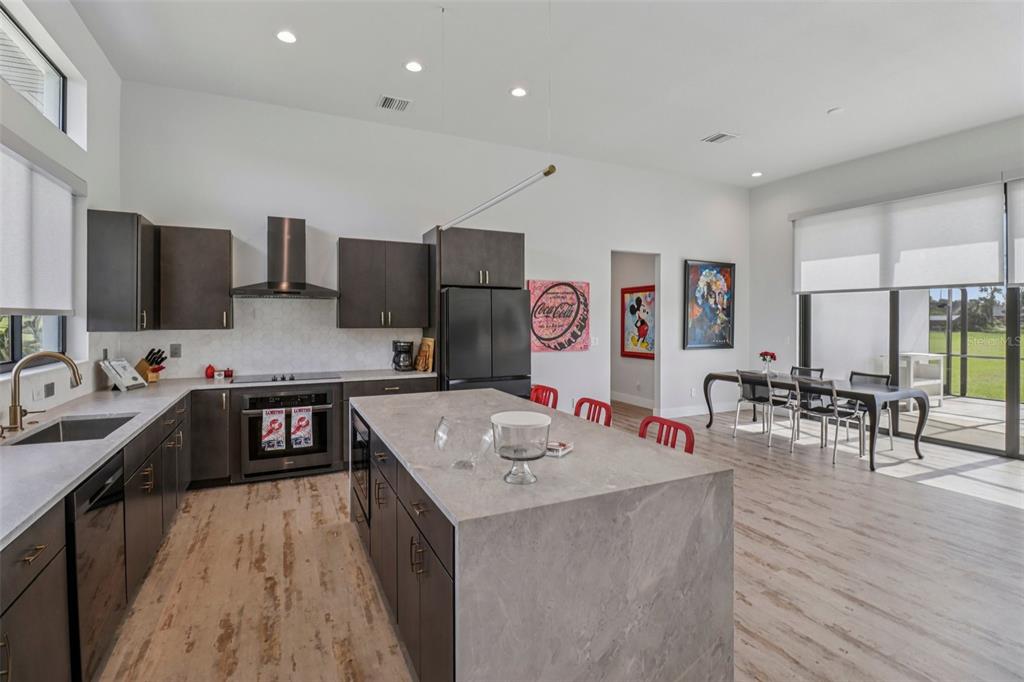 3385 Lake Diane Road Tavares, FL 32778 - Photo 11 of 49 a kitchen with stainless steel appliances granite countertop a refrigerator a sink dishwasher a stove and a dining table with wooden floor