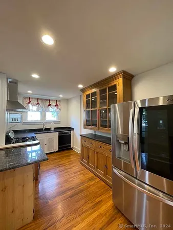 a kitchen with stainless steel appliances wooden floor and large window