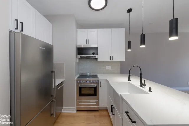 a kitchen with stainless steel appliances a sink a stove a refrigerator and cabinets
