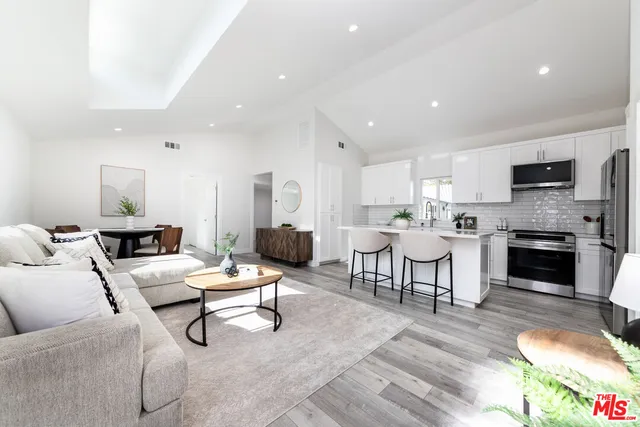 a living room with furniture and a fireplace with kitchen view